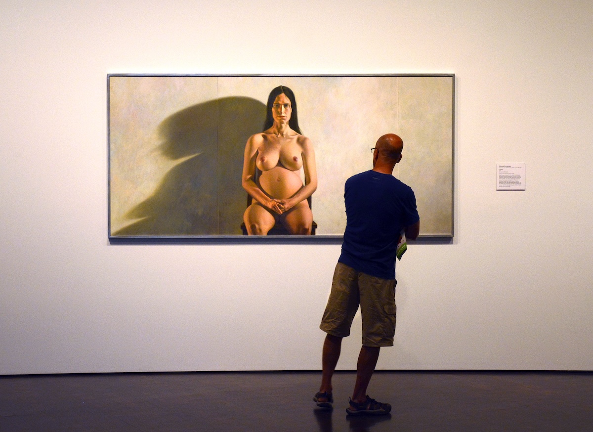 Un uomo osserva un dipinto raffigurante una donna incinta nuda 