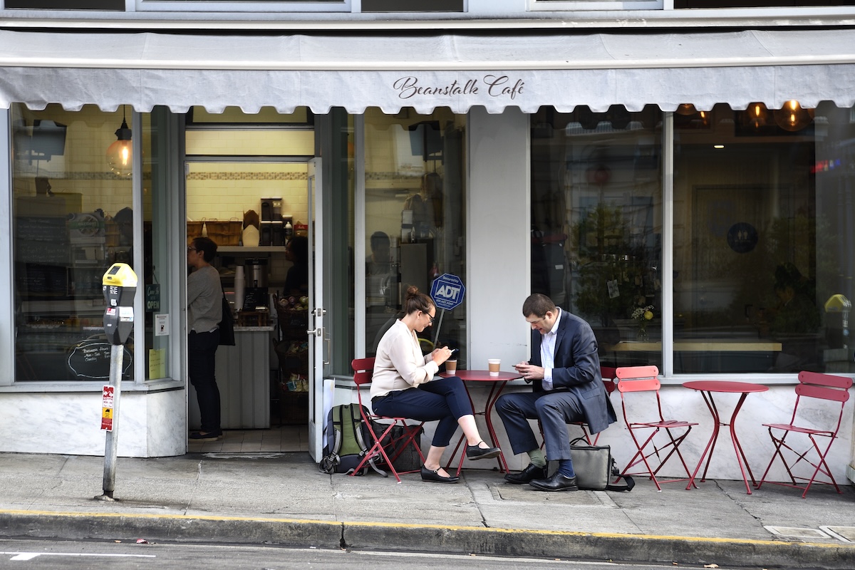 Due persone dialogano mentre guardano i loro rispettivi smartphone