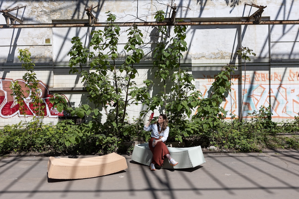 Una visitatrice seduta a una mostra solleva il suo smartphone per scattare una foto 