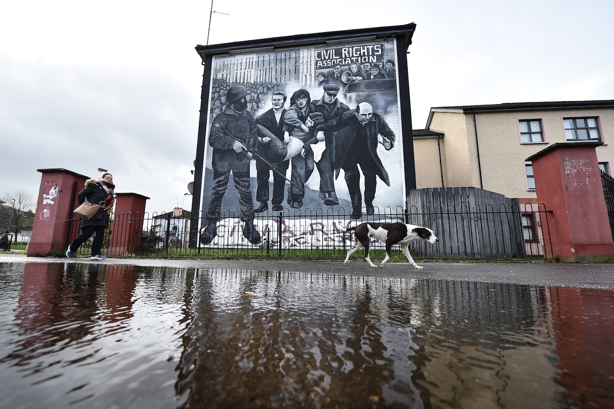 Una donna e un cane passano davanti a un murale