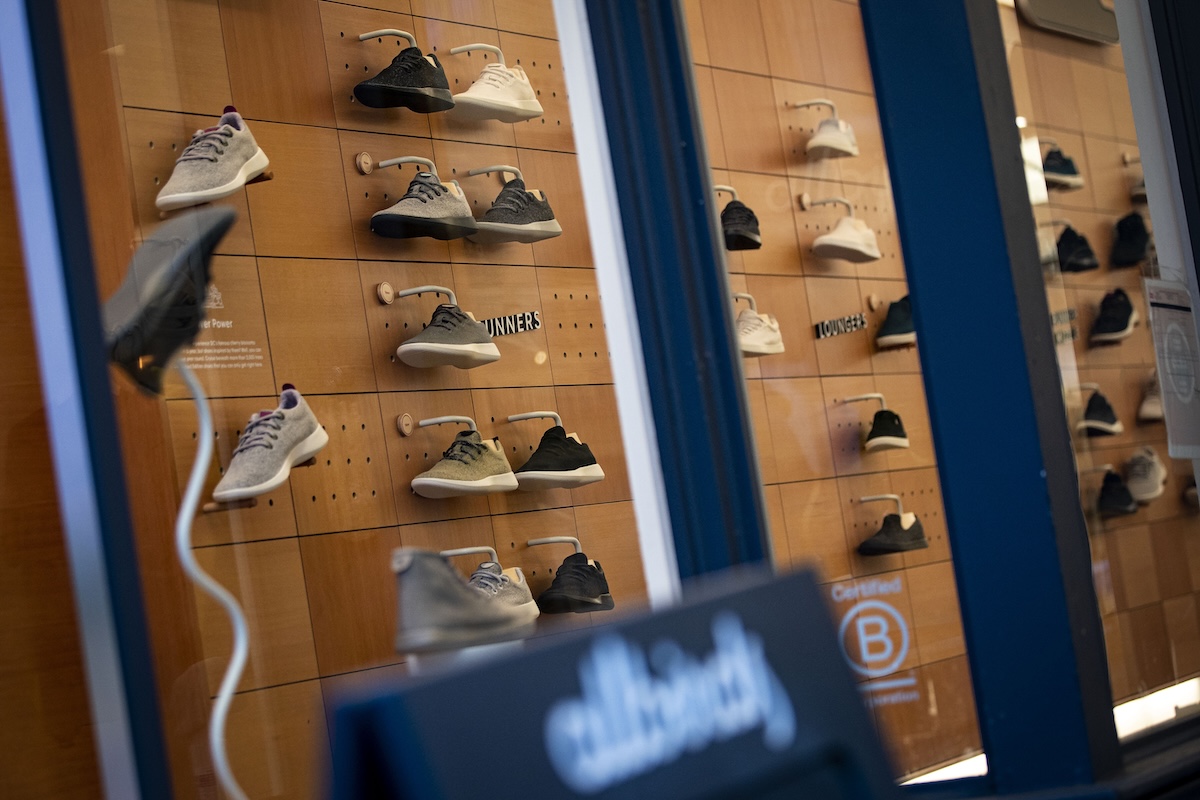 Alcune scarpe esposte sulla parete di un negozio, fotografate dall'esterno attraverso la vetrina 