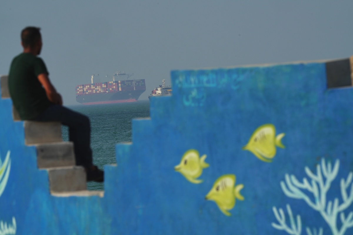 Un uomo osserva una nave cargo nello stretto di Hormuz, dall'isola iraniana di Qeshm, il 28 aprile