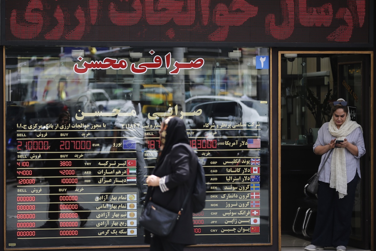 Due donne fuori da un cambiavalute di Teheran, il 4 maggio; sulla vetrina ci sono le quotazioni per cambiare il rial, la valuta iraniana, con altre valute