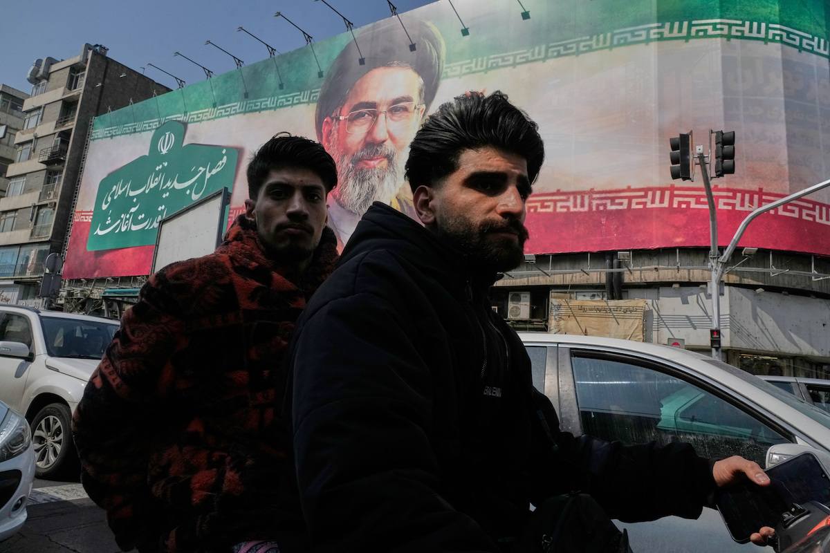 Due uomini davanti a un manifesto di Khamenei a Teheran, marzo 2026 (AP Photo/Vahid Salemi)