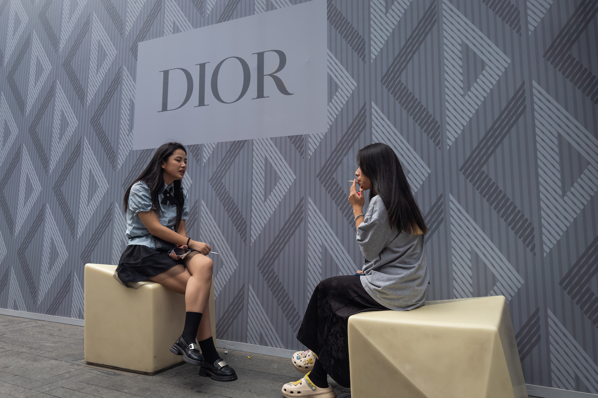 Due ragazze fumano davanti a un negozio di Dior a Chengdu, settembre 2024 (Cheng Xin/Getty Images)