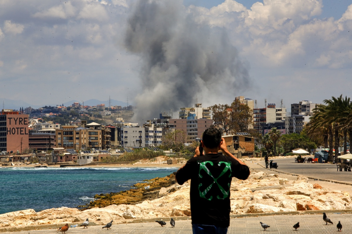 Un ragazzo filma il fumo causato da un attacco israeliano su Tiro, il 29 maggio