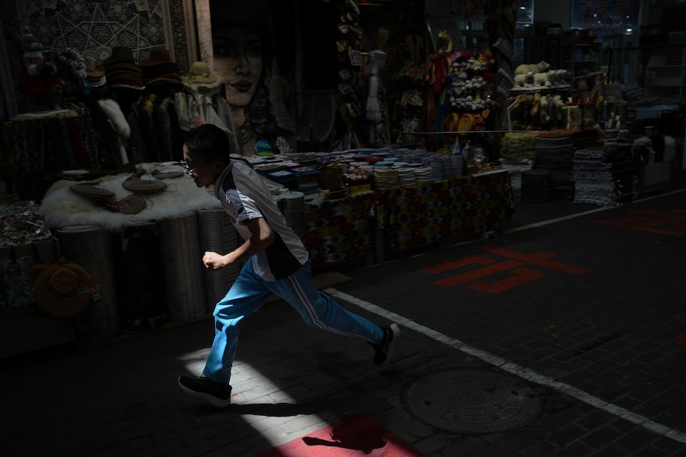 Un bambino corre in un mercato nella prefettura di Altay, nella regione autonoma uigura dello Xinjiang(AP Photo/Andy Wong)
