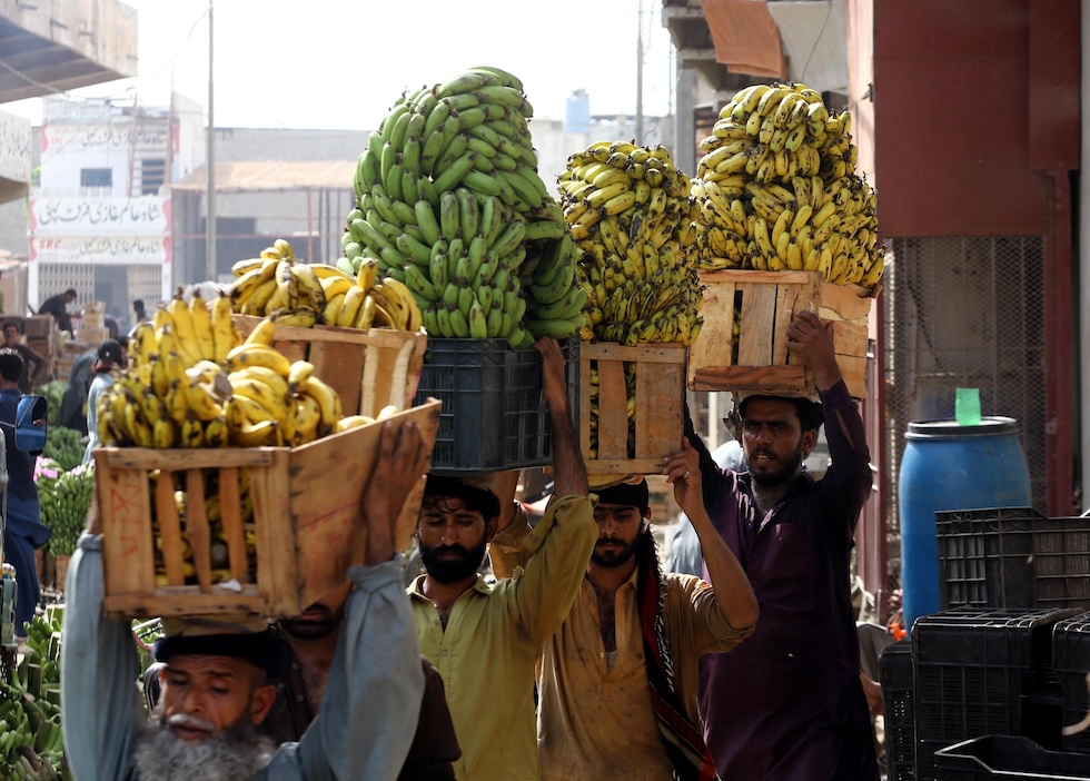 Fruttivendoli con casse di banane in un mercato (EPA/REHAN KHAN/ansa)
