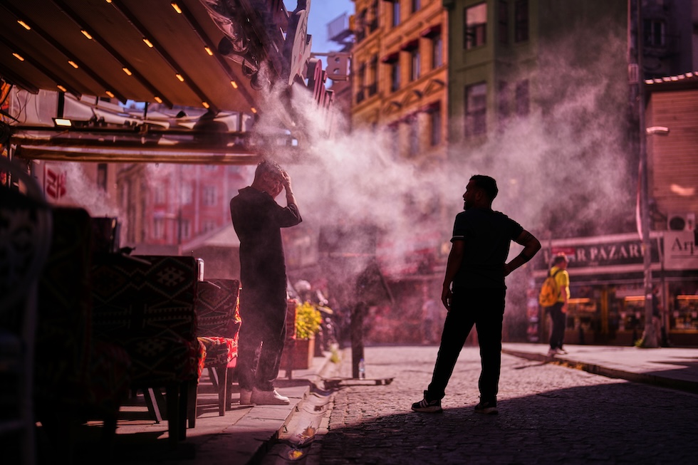 Due persone si rinfrescano sotto dei nebulizzatori d'acqua fuori da un ristorante (AP Photo/Francisco Seco)