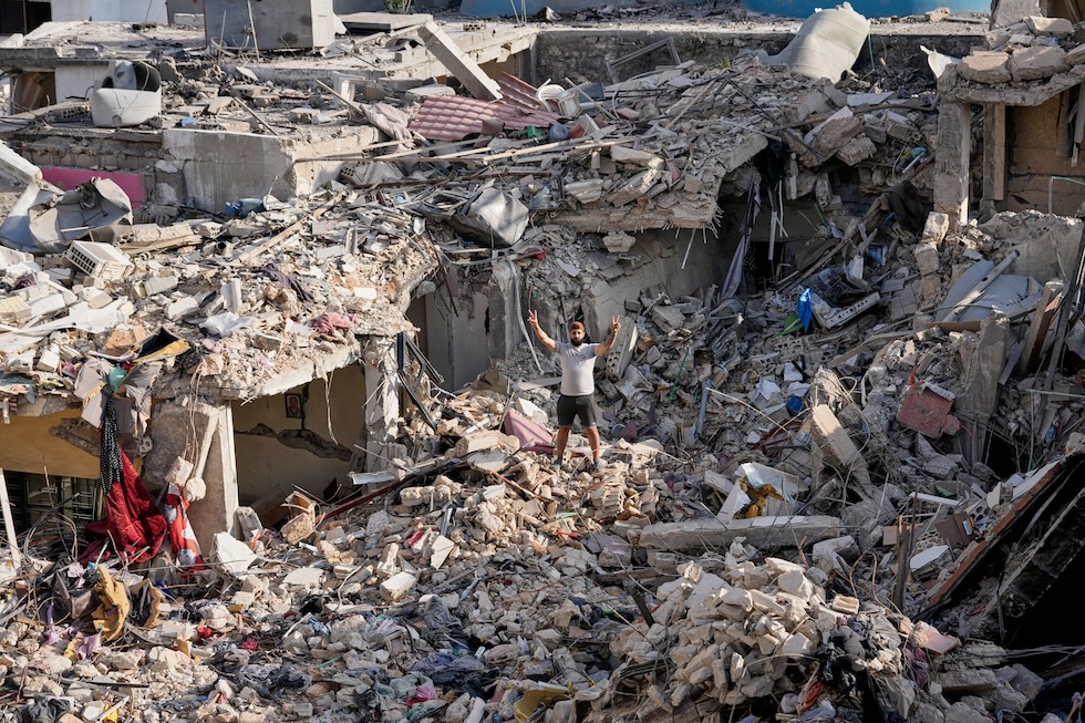 Un uomo, tornato a Nabatieh dopo l'annuncio dell'accordo tra Stati Uniti e Iran, fa il segno della vittoria sopra le macerie di casa sua, distrutta dai bombardamenti (AP Photo/Hussein Malla)