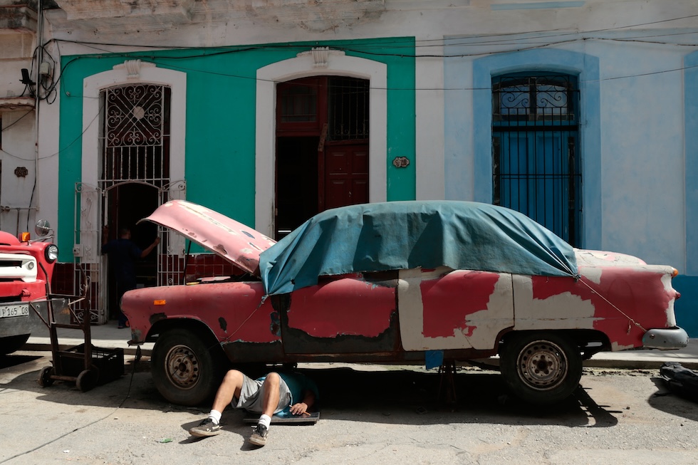 Un uomo lavora su un'auto americana d'epoca (AP Photo/Jorge Luis Banos)