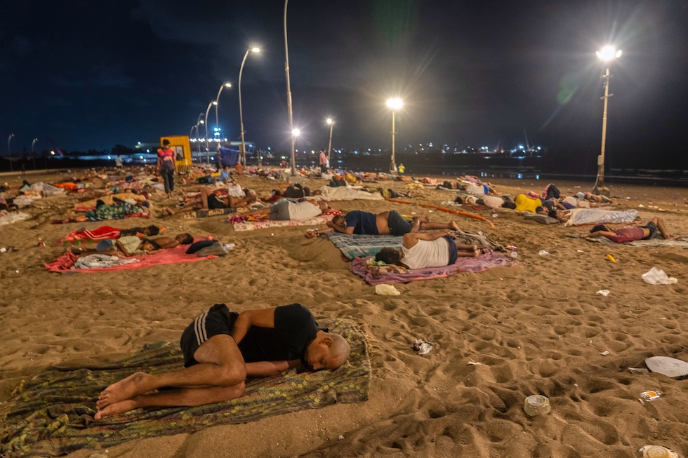 Persone che hanno dormito in spiaggia per trovare un po' di sollievo dal caldo  (AP Photo/Rafiq Maqbool)
