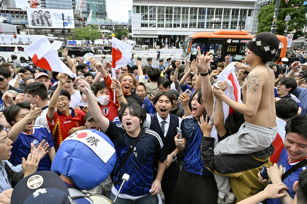 Tifosi festeggiano la vittoria della nazionale giapponese contro la Tunisia in una partita dei Mondiali di calcio nella zona del famoso incrocio di Shibuya a Tokyo
(Takahiko Sato/Kyodo News via AP)