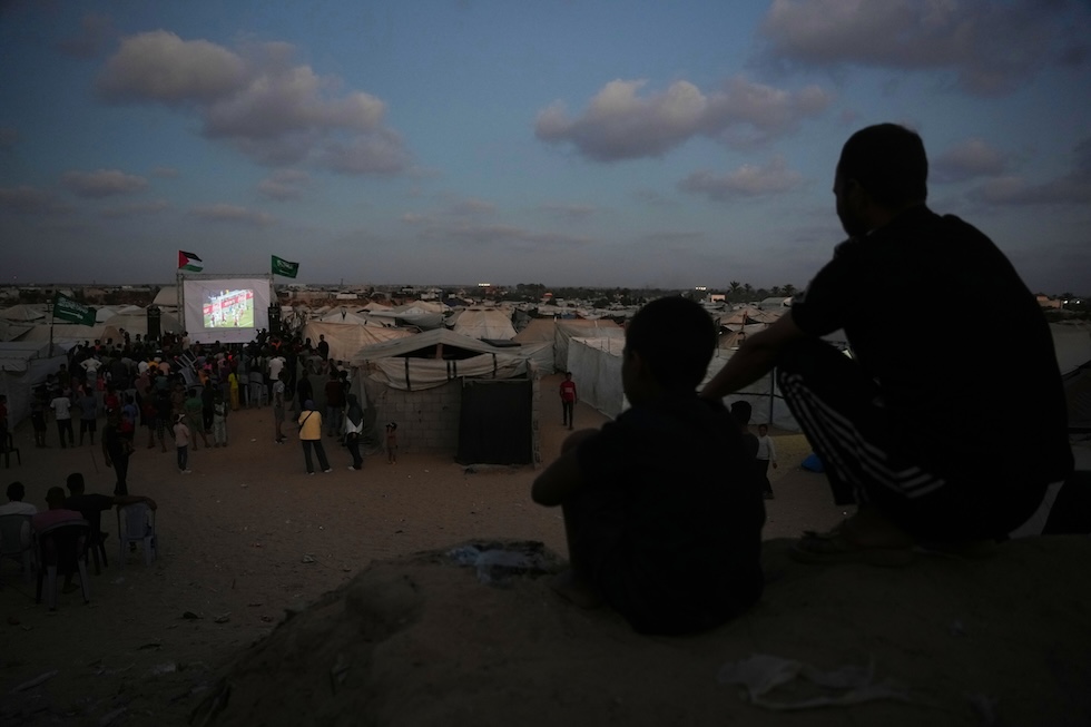 Alcuni palestinesi guardano la partita dei Mondiali tra Spagna e Arabia Saudita su uno schermo nel campo profughi di Nuseirat, ieri 21 giugno (AP Photo/Abdel Kareem Hana)