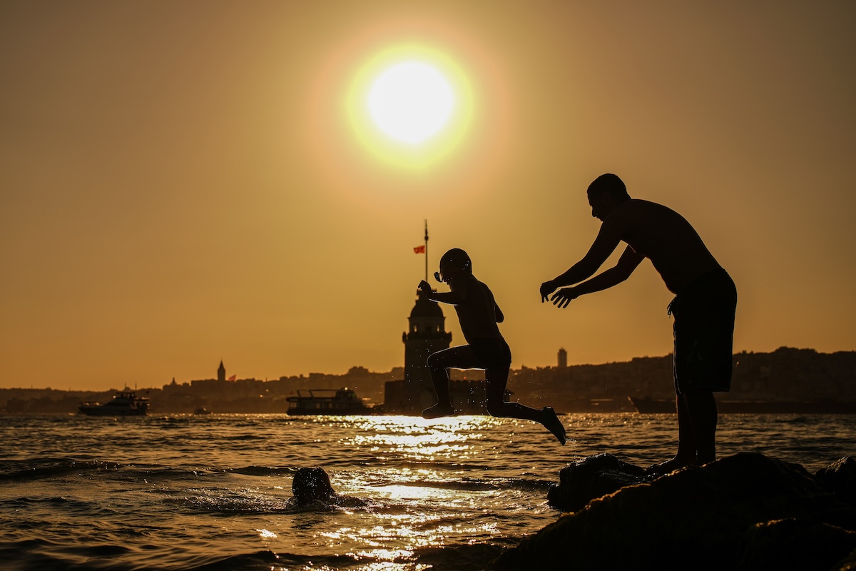 Alcune persone si tuffano in acqua al tramonto a Istanbul, in Turchia, il 28 giugno (AP Photo/Emrah Gurel)