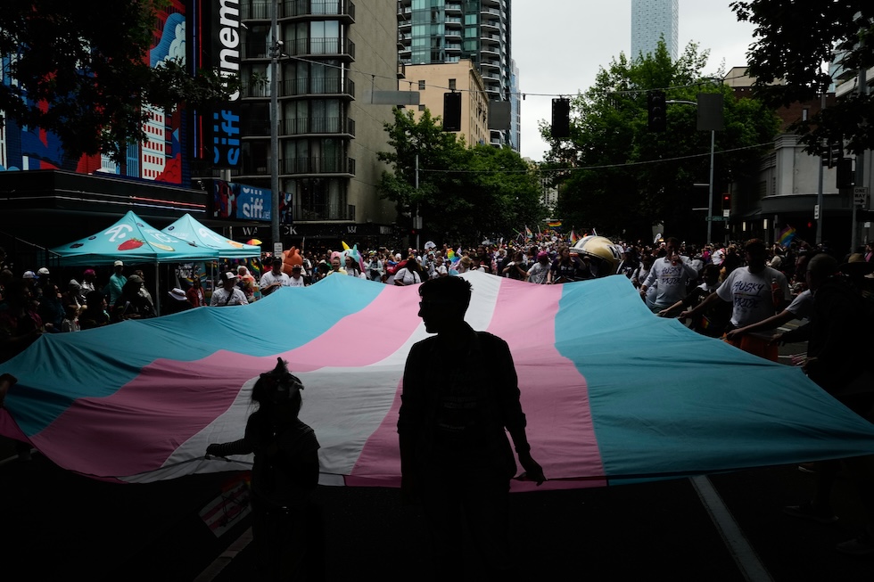 Alcune persone portano una bandiera dell'orgoglio transgender alla parata del Pride (AP Photo/Lindsey Wasson)
