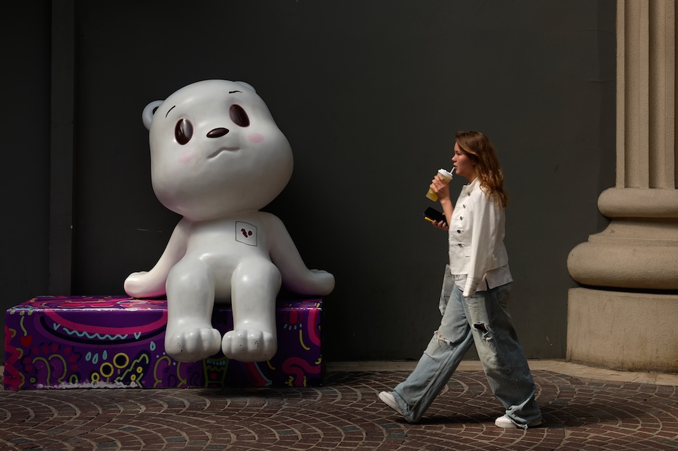 Una donna passa davanti a una statua esposta all'esterno di un centro commerciale (AP Photo/Andy Wong)
