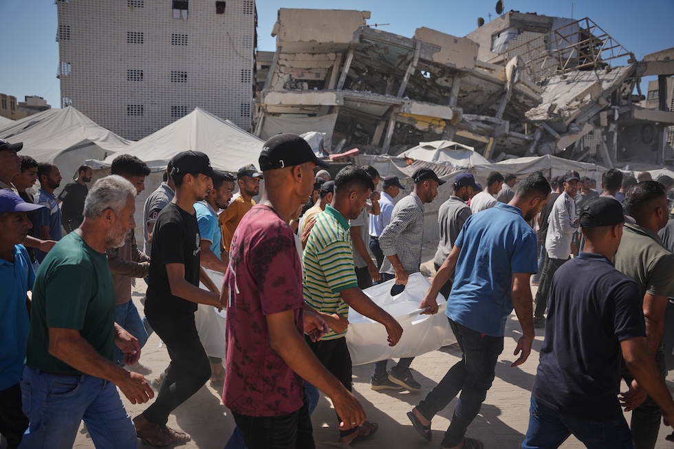 Persone palestinesi trasportano il corpo di una donna uccisa in un bombardamento aereo israeliano (AP Photo/Abdel Kareem Hana)
