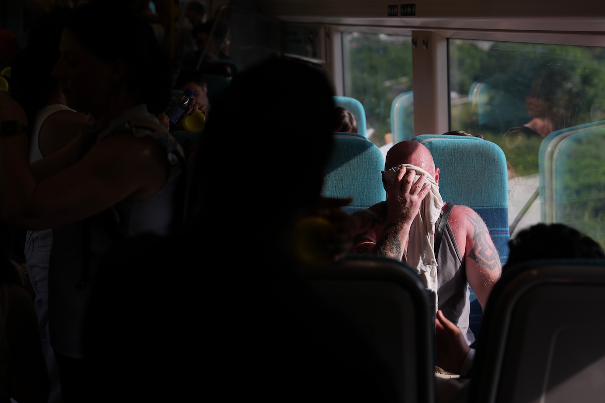 Un passeggero su un treno si asciuga il sudore dalla fronte