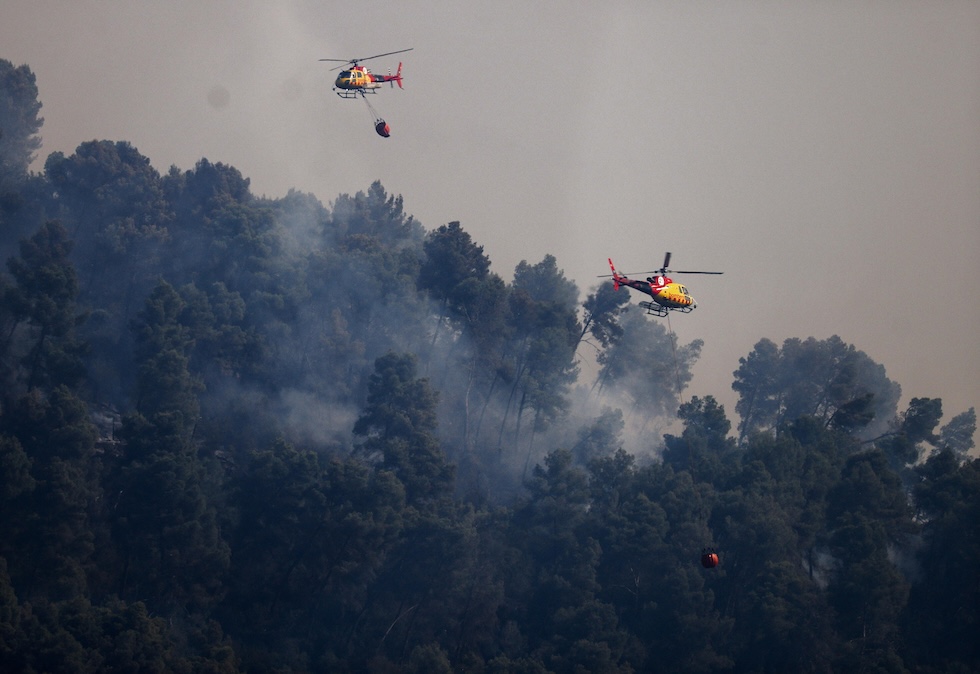 Due elicotteri cercano di spegnere un incendio boschivo (EPA/Quique Garcia/Ansa)