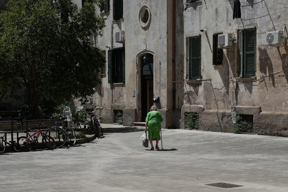Una signora anziana cammina in un cortile nel quartiere Testaccio (AP Photo/Alessandra Tarantino)