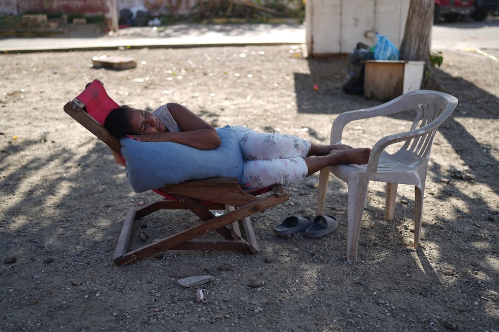Una donna riposa su una sdraio, vicino agli edifici crollati per il terremoto (AP Photo/Ariana Cubillos)