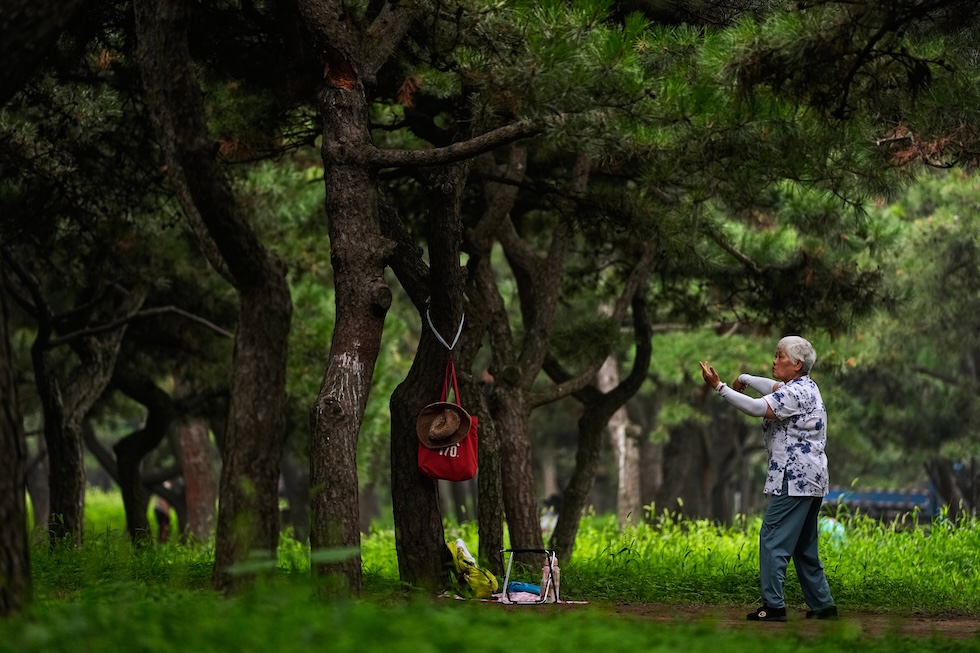 Una donna anziana pratica il tai-chi in un parco vicino al Tempio del Cielo (AP Photo/Andy Wong)