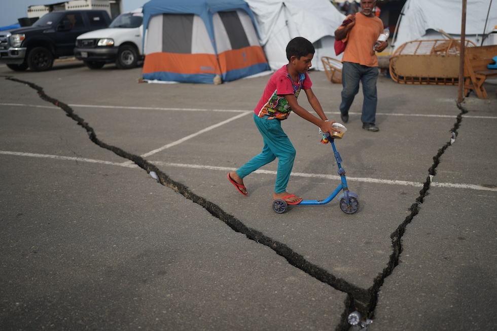 Un bambino su un monopattino in un rifugio allestito in un parcheggio dopo i forti terremoti (AP Photo/Ariana Cubillos)
