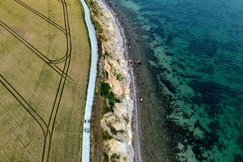 Persone in bicicletta lungo una strada accanto alla costa rocciosa del mar Baltico (AP Photo/Michael Probst)