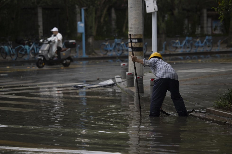Un operaio chiude la griglia di uno scarico in una strada allagata dopo il passaggio del tifone Bavi. (EPA/ANDRES MARTINEZ CASARES)