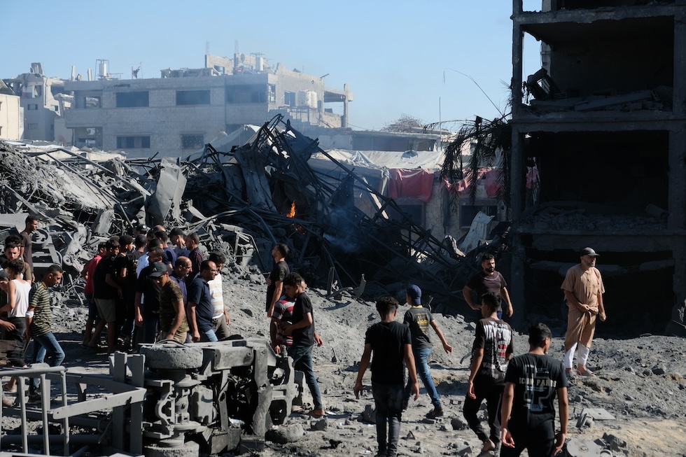 Alcuni palestinesi si radunano attorno al luogo di un attacco di droni militari israeliani. (AP Photo/Jehad Alshrafi)