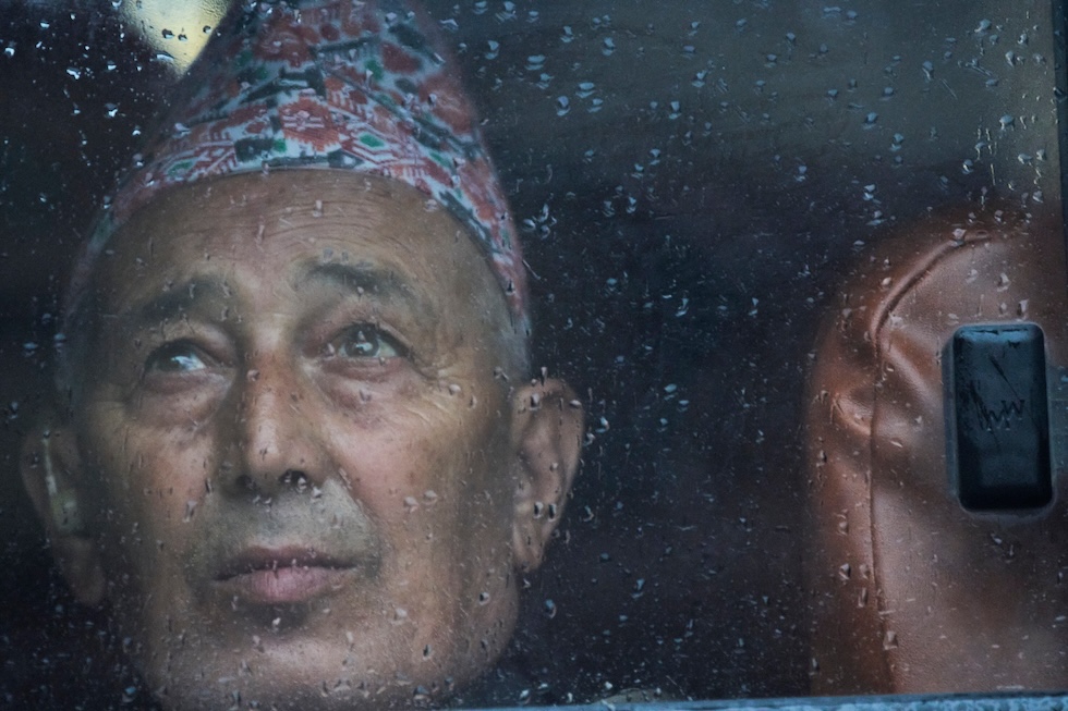 Un uomo dietro il finestrino di un autobus bagnato dalla pioggia (AP Photo/Niranjan Shrestha)