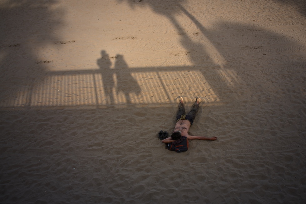 Un uomo steso sulla spiaggia (AP Photo/Emilio Morenatti)