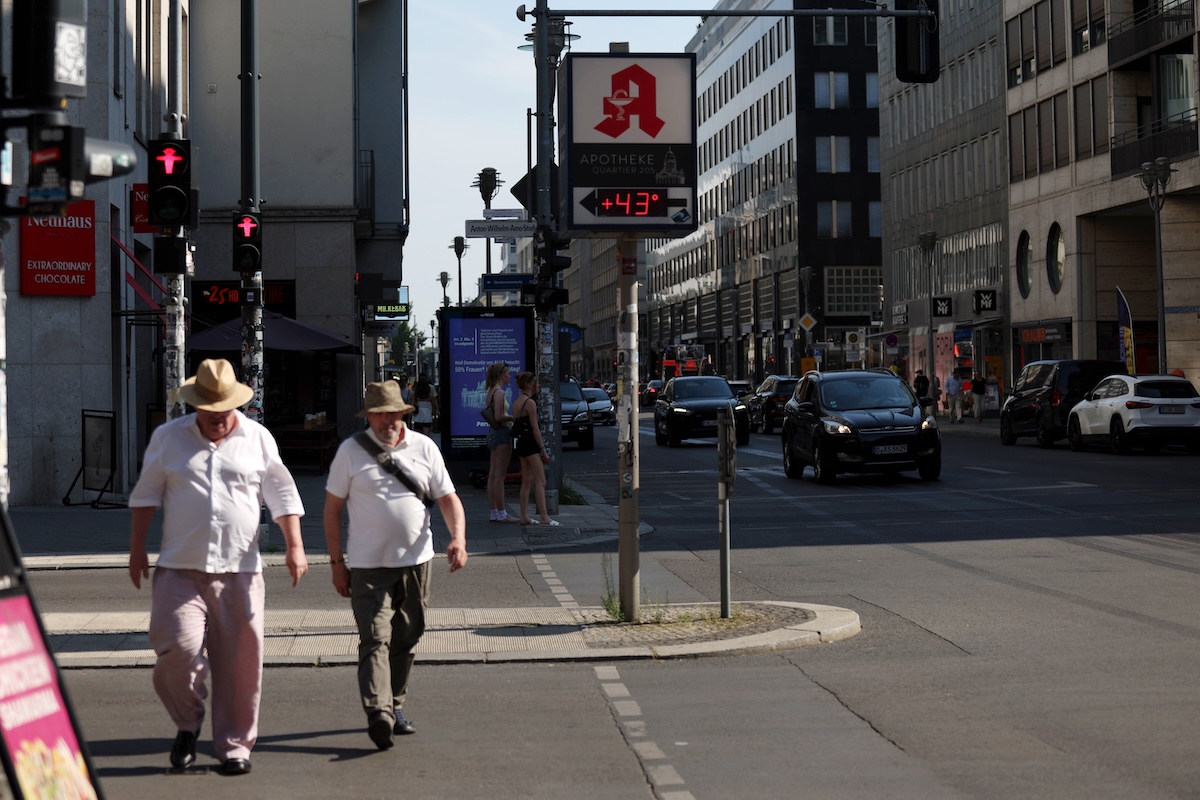 Due persone attraversano una strada, mentre il termometro segna +43 °C