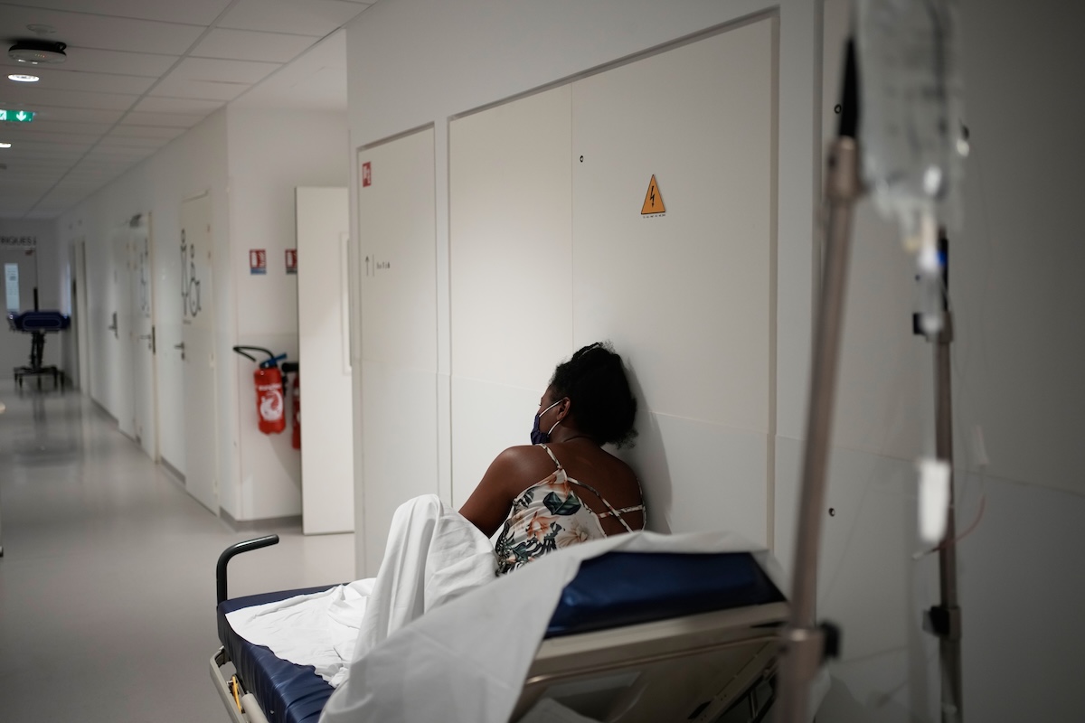 Una paziente seduta su un lettino e appoggiata a una porta