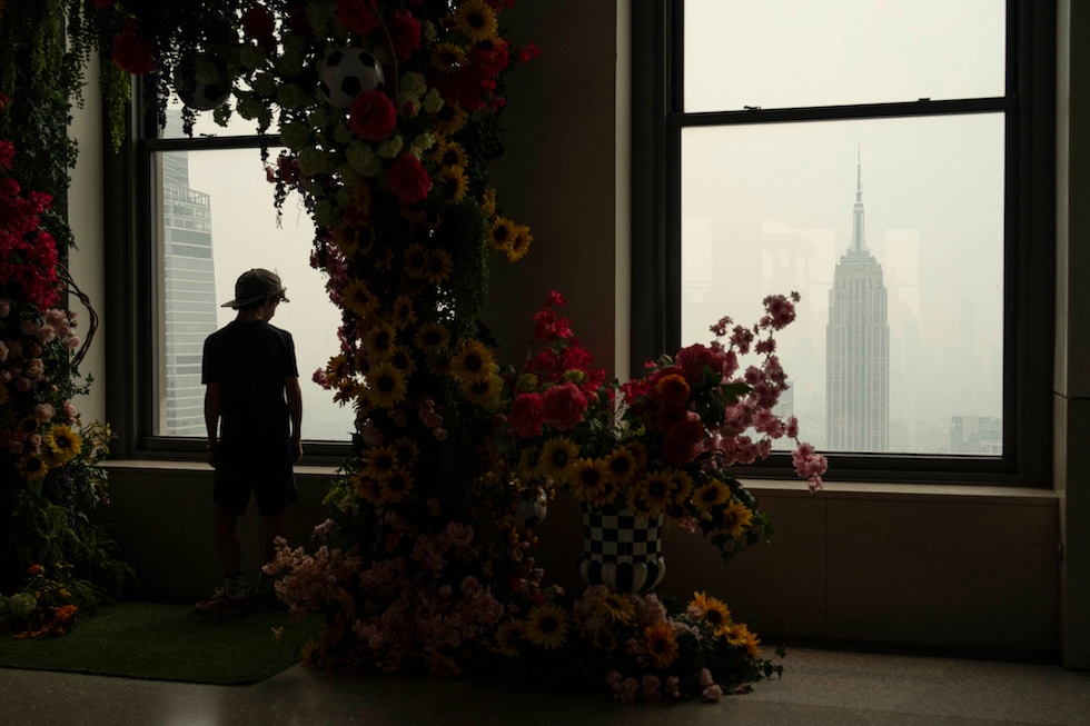 Una persona affacciata a una finestra della piattaforma panoramica Top of the Rock mentre il fumo degli incendi boschivi in Canada avvolge la città (AP Photo/Yuki Iwamura)