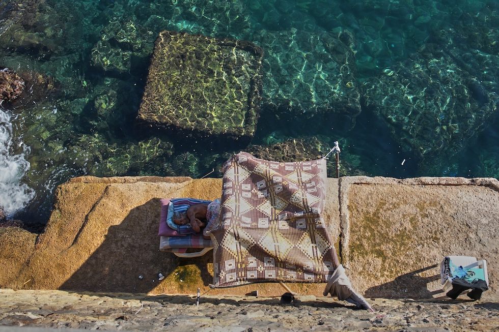 Un uomo dorme sul lungomare (AP Photo/Hassan Ammar)