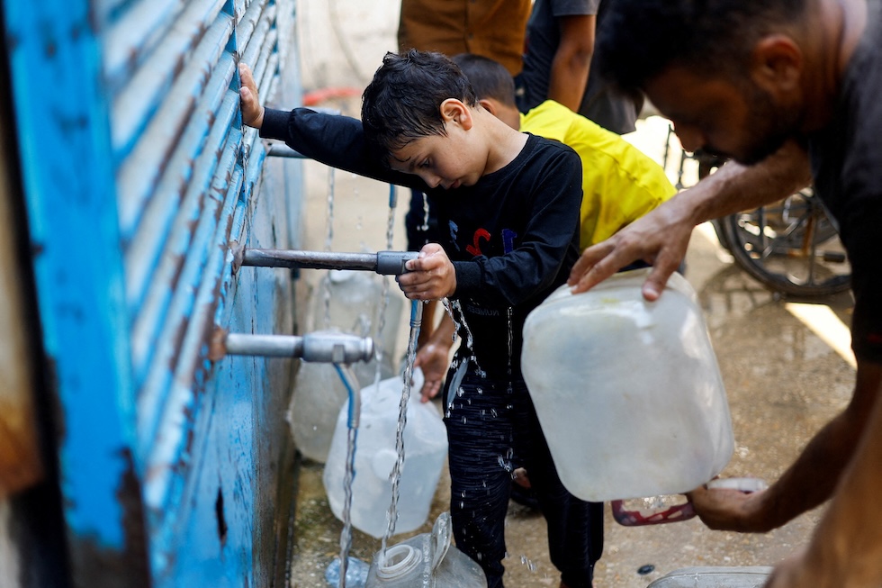Palestinesi riempiono delle taniche in un punto di distribuzione dell'acqua (REUTERS/Mahmoud Issa)