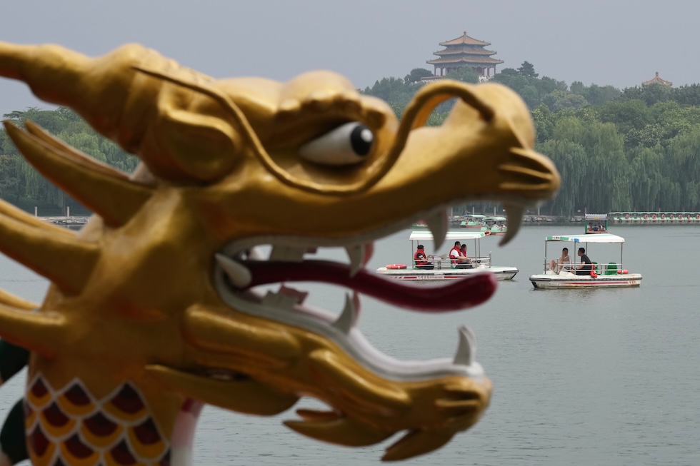 Turisti in barca sul lago del parco Beihai, con sullo sfondo il padiglione Wanchun nel parco Jingshan (AP Photo/Andy Wong)