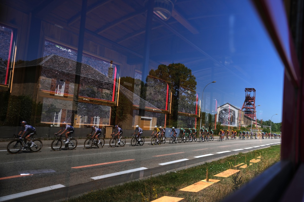 Ciclisti riflessi in una finestra durante la diciottesima tappa del Tour de France, con partenza da Voiron e arrivo a Orcières-Merlette (AP Photo/Thibault Camus)