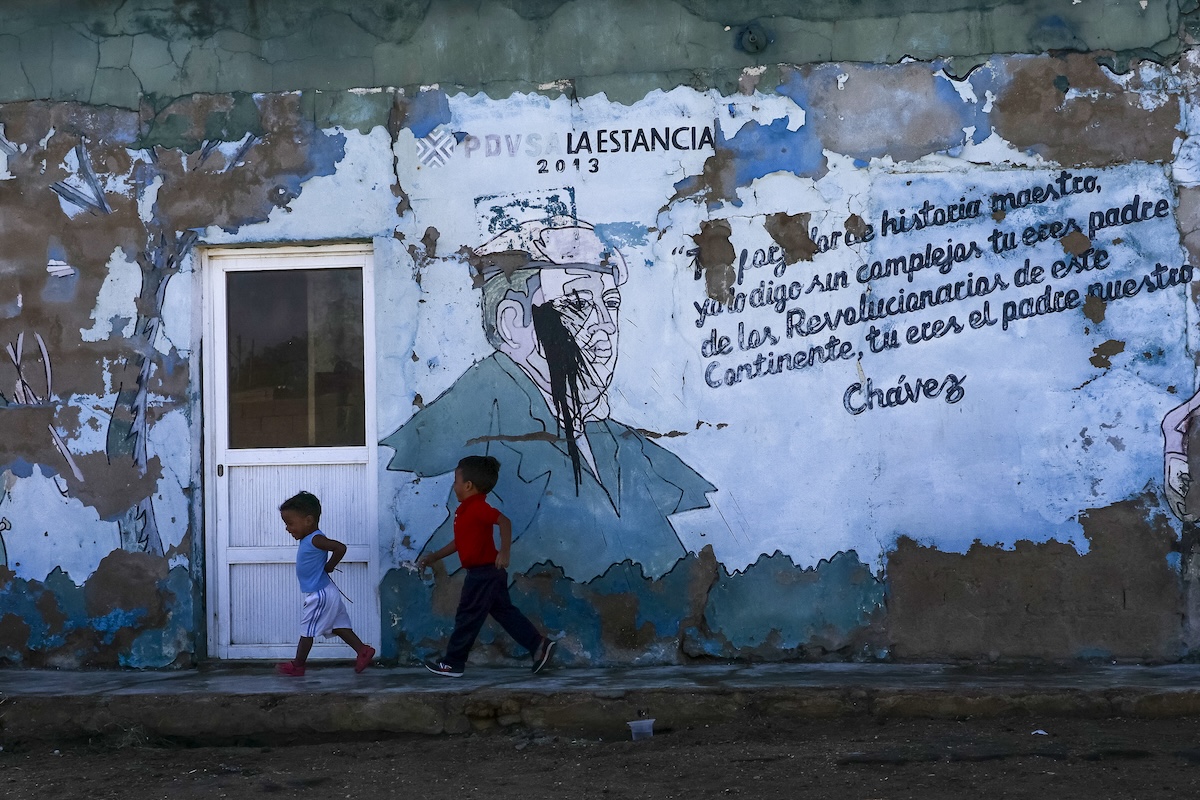 Due bambini davanti a un murale sgretolato con una frase di Hugo Chávez, fondatore del regime venezuelano, a Punta Cardón lo scorso 23 gennaio