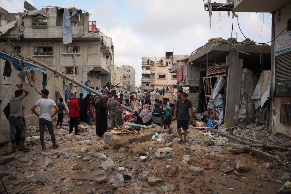 Palestinesi tra le macerie di edifici distrutti da un bombardamento israeliano (AP Photo/Abdel Kareem Hana)