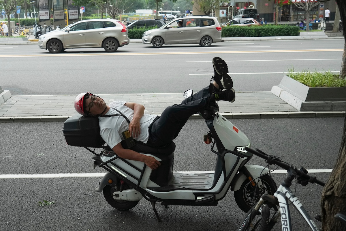 Un uomo si riposa sul suo scooter (AP Photo/Achmad Ibrahim)