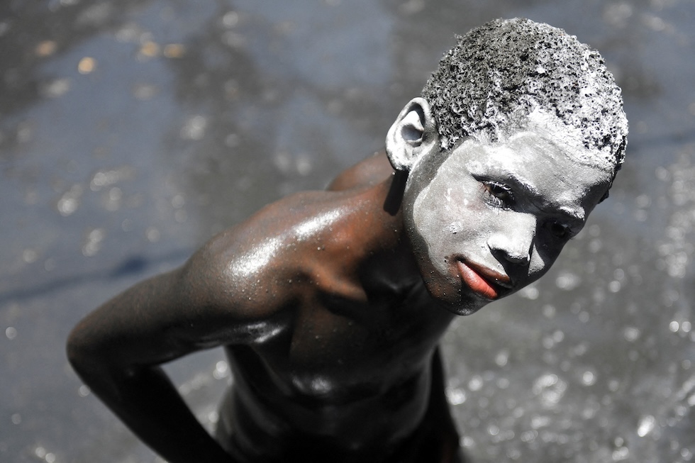 Un bambino con il viso coperto di argilla bianca partecipa a un bagno rituale nel bacino di Saint-Jacques durante il pellegrinaggio annuale in onore di san Giacomo il Maggiore, che fonde tradizioni cattoliche e vudù (REUTERS/Johnson Sabin)
