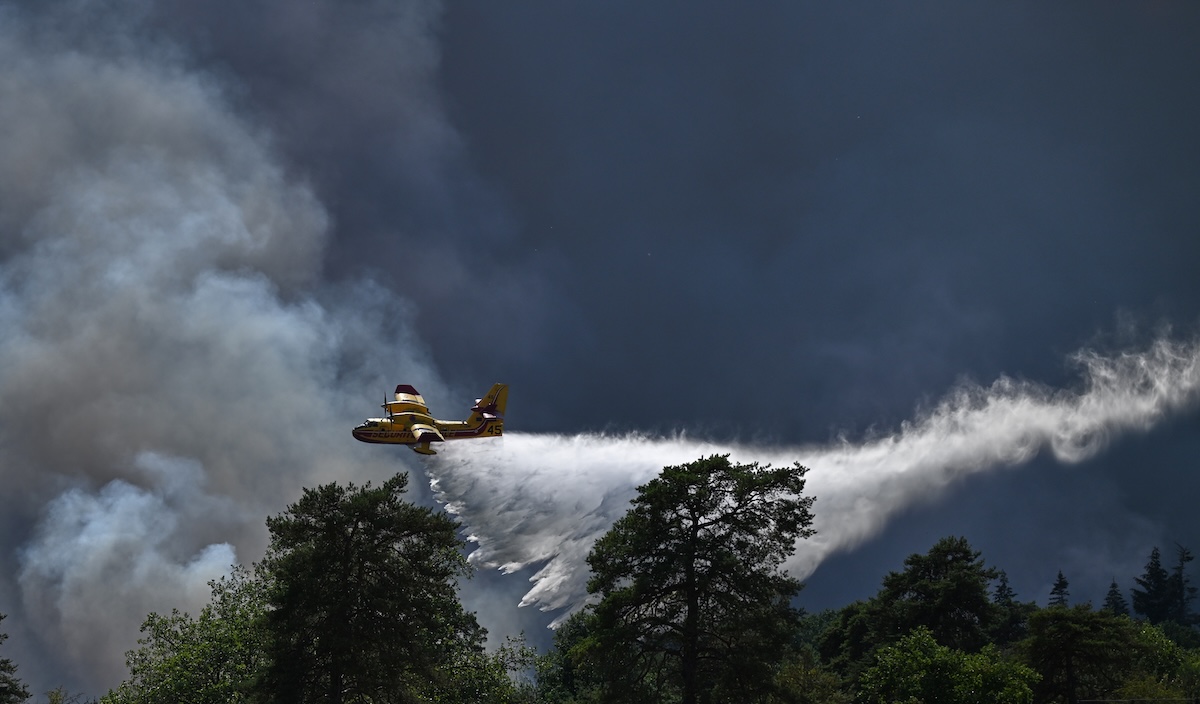 Un Canadair in volo sopra un incendio nella foresta di Fontainebleau, vicino a Parigi, il 13 luglio 2026 (AP/Emma Da Silva)