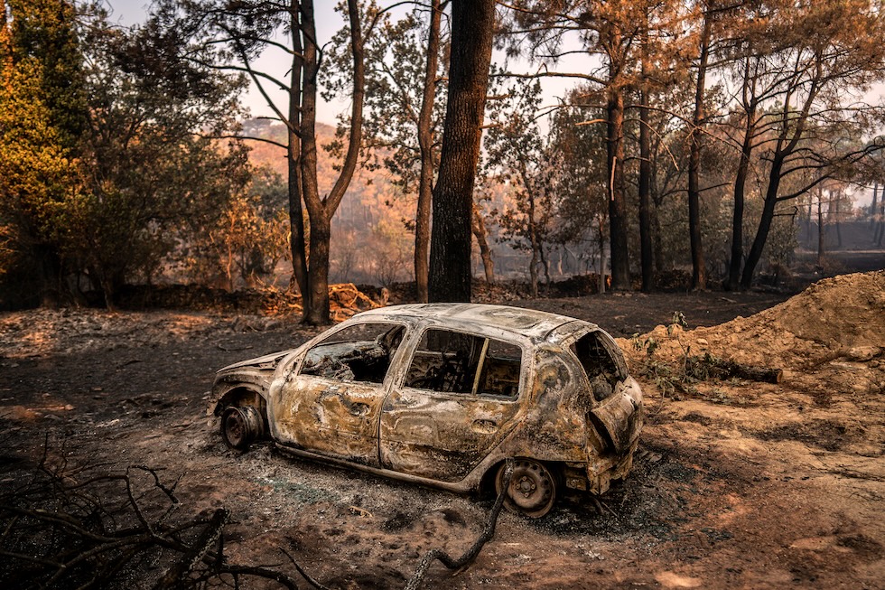 Un'auto bruciata in un'area devastata dagli incendi boschivi (AP Photo/Olmo Calvo)