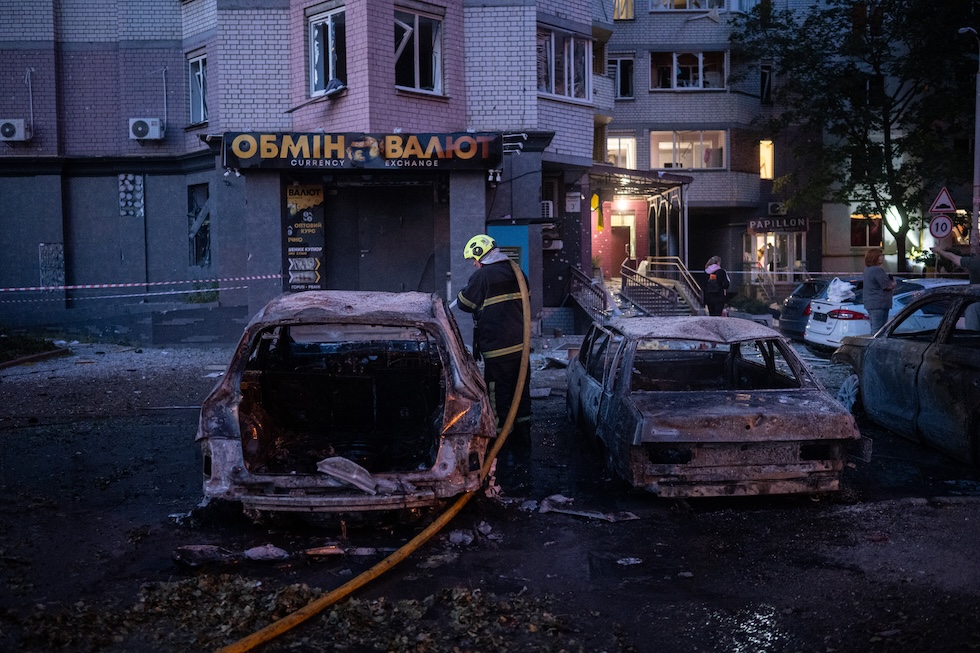 Un vigile del fuoco vicino ad un'auto distrutta e un edificio colpito da un attacco missilistico russo su Kiev, in Ucraina, in cui almeno nove persone sono state uccise e altre 27 ferite (Danylo Antoniuk/Anadolu via Getty Images)