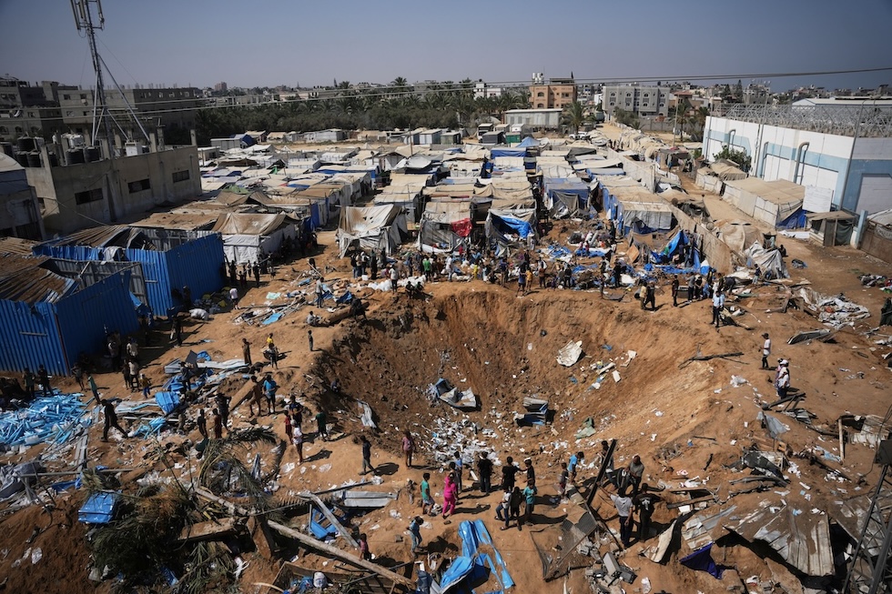 I detriti e una grossa buca creata da un attacco aereo israeliano vicino all’ospedale al-Aqsa a Deir al Balah, nella Striscia di Gaza (AP/Abdel Kareem Hana)
