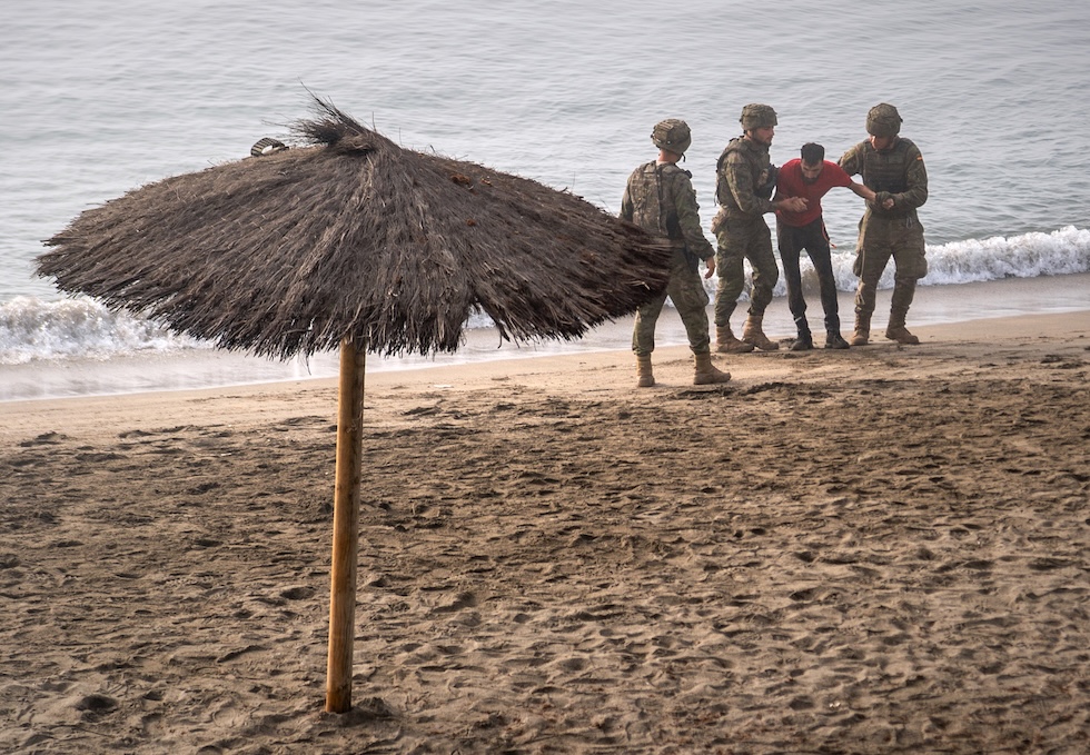 Alcuni soldati spagnoli che prestano soccorso a una persona che ha raggiunto a nuoto l’enclave spagnola di Ceuta partendo a nuoto dal Marocco (AP/Antonio Sempere)