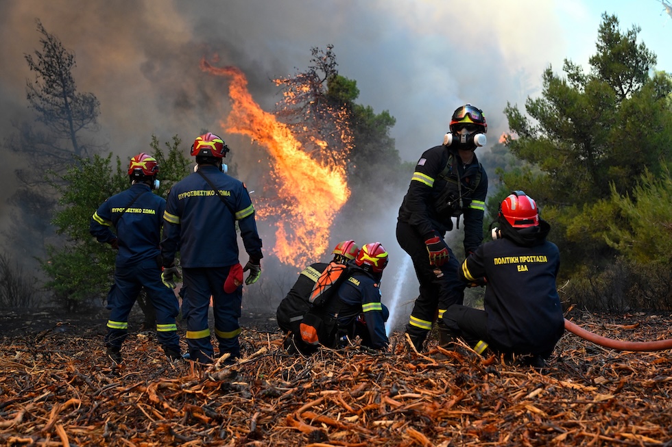 Alcuni vigili del fuoco davanti a una foresta in fiamme vicino a Porto Germeno, a nord-ovest di Atene (AP/Michael Varaklas)